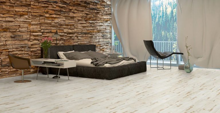 Modernes Schlafzimmer mit einer Akzentwand aus Stein, einem Podestbett, einem Sessel, einem Schreibtisch und großen Fenstern mit transparenten Vorhängen, die einen Blick auf den Wald freigeben, mit stilvollem Vinylbelag, der von einem professionellen Bodenleger fachmännisch installiert wurde. -Bodenstyle Schuster - Industriestraße 2 - 66802 Überherrn - +49 (0)6836-7789955