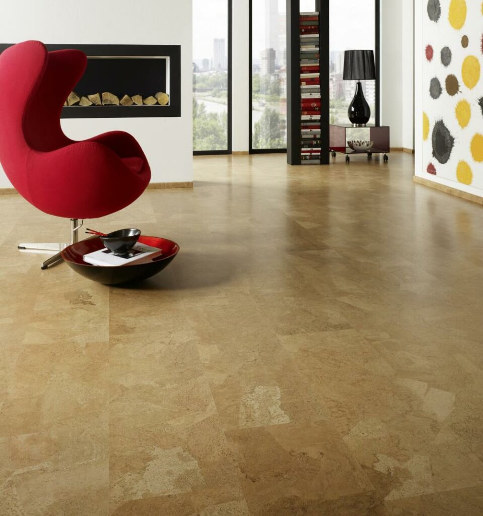 Modernes Wohnzimmer mit hellbraunem Laminatboden, einem roten Eiersessel, einer dekorativen Schale, einem Bücherregal, einem Kamin, einer Stehlampe, einem großen Fenster und abstrakter Kunst an der Wand. -Bodenstyle Schuster - Industriestraße 2 - 66802 Überherrn - +49 (0)6836-7789955